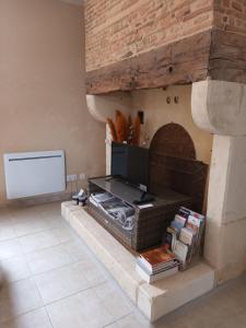 a living room with a stone fireplace with a tv at GÎTE AUX BOIS D'EN TEMPS in Lunas