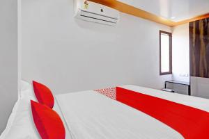 a bedroom with a white bed with red accents at Super OYO Flagship 81158 Hotel Aditya Inn in Patna