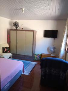 Schlafzimmer mit einem Bett und einem Flachbild-TV in der Unterkunft Casa da Lu in Macaé