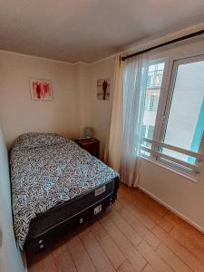 a bedroom with a bed and a large window at Departamento en Calama in Calama