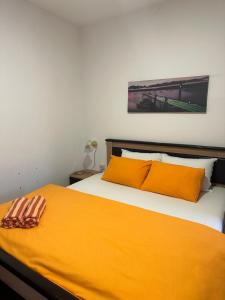 Una cama con dos almohadas naranjas encima. en Apartmani Vučinić, en Cetinje