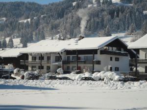 ein schneebedecktes Gebäude mit davor geparkt in der Unterkunft Ferienwohnung "Alpenglück" mit Hallenbad in Bolsterlang