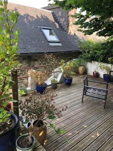 eine Holzterrasse mit Topfpflanzen und einer Bank darauf in der Unterkunft Les Hauts de Morlaix in Morlaix