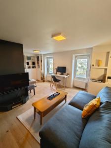 ein Wohnzimmer mit einem blauen Sofa und einem Flachbild-TV in der Unterkunft Les Hauts de Morlaix in Morlaix