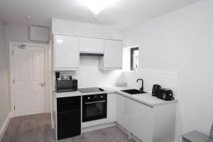a kitchen with white cabinets and a black dishwasher at New Cosy Studio in London! in London