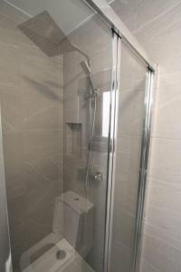 uma casa de banho com uma cabina de duche em vidro e um WC. em New Cosy Studio in London! em Londres