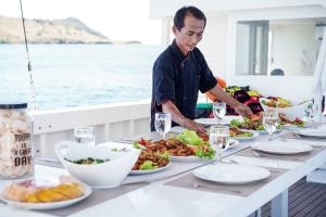 a man standing at a table with plates of food at Phinisi charter in Labuan Bajo in Labuan Bajo