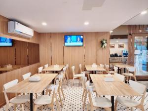 un restaurant avec des tables en bois et des chaises blanches dans l'établissement Nakara Hotel, Ubon Ratchathani, à Ban Na Kham