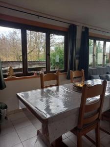 a dining room with a table and chairs and windows at Chalet - l'Endoxyle in Froid-Chapelle