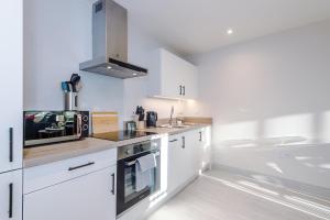 a kitchen with white cabinets and a stove top oven at Stunning Flat in Central Leeds by PureStay Short Stays in Leeds