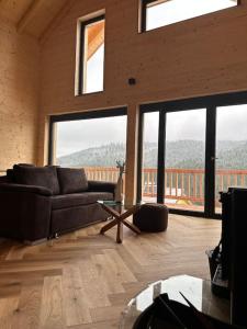 a living room with a couch and large windows at Ferienhaus am Sommerberg in Vöhrenbach