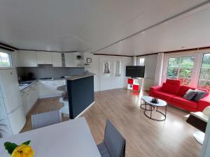een keuken en een woonkamer met een rode bank bij Comfort chalet nr. 19 in Putten