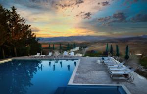 a swimming pool with white lounge chairs and a sunset at Glamping Diacceroni in Villamagna