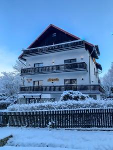 un gran edificio blanco con una valla en la nieve en Jeleni Ruczaj, en Karpacz