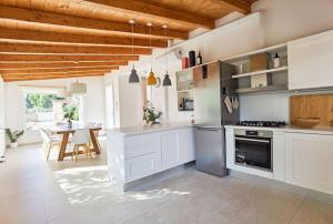une grande cuisine avec des placards blancs et une table dans l'établissement La Sarina Luxury near Gallipoli, à Matino