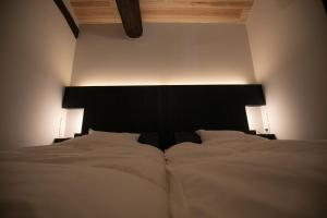 um quarto com uma grande cama branca e uma cabeceira preta em オーベルジュ キャトル セゾン 宗像 em Akama