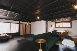 uma sala de estar com um sofá verde e mesas em オーベルジュ キャトル セゾン 宗像 em Akama