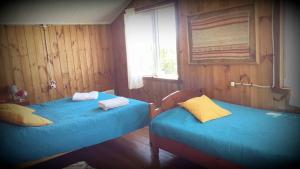two beds in a room with wood paneling at Hostería Miller FRENTE AL MAR in Bahía Mansa