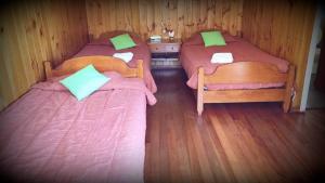 2 camas en una habitación con suelo de madera en Hostería Miller FRENTE AL MAR, en Bahía Mansa