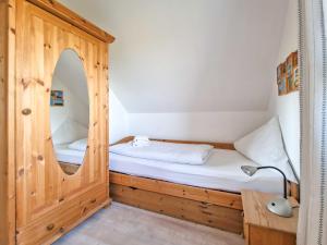 ein kleines Schlafzimmer mit einem Bett und einem Spiegel in der Unterkunft Deichtraum in Greetsiel
