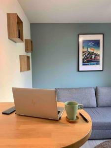 a laptop on a table in a living room with a couch at Studio Le Pensier - Monplaisir in Lyon