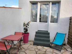 patio con sedie, tavolo e porta di Dormez au coeur du village entre plage et polder a Barbâtre