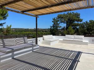 two white benches sitting on a patio at Casa da Pergola - Beach Design Villa Private Pool in Santo André