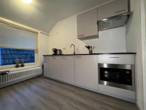 uma cozinha com armários brancos e um forno com placa de fogão em Appartement met prachtig uitzicht over de binnenstad van Leeuwarden em Leeuwarden