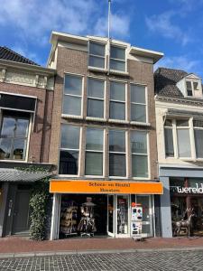uma loja em frente a um edifício de tijolos com uma loja laranja em Appartement met prachtig uitzicht over de binnenstad van Leeuwarden em Leeuwarden