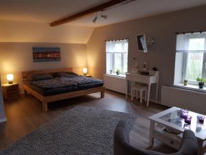 Un dormitorio con una cama y una mesa y ventanas. en Ferienwohnung Haloi, en Torsballig