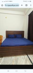 a bedroom with a bed with blue sheets and blue pillows at राम जानकी भवन होम स्टे in Faizābād