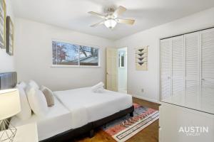 a white bedroom with a bed and a ceiling fan at Essence of Austin Fully Equipped and Stylish Abode in Austin