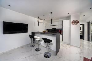 a kitchen with white walls and a counter with stools at Royal House 3 in Pašman