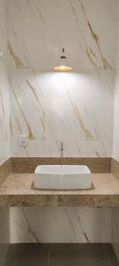 a white sink in a bathroom with marble walls at Apt em Edifício Frente a Praia Areia Preta in Guarapari