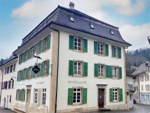 - un bâtiment blanc et vert avec volets verts dans l'établissement Hôtel de La Cigogne, à Saint-Ursanne