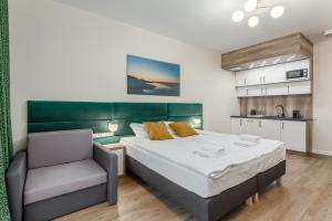 a bedroom with a large bed and a chair at Deo Plaza Apartamenty Premium in Gdańsk