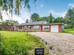 a brick house with a garage on a gravel driveway at 4 Bed in Holt 83070 in Sharrington