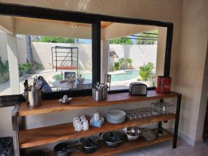 a kitchen with a mirror above a shelf with dishes at Tiny Villa Votre Villa Privatisée in Ndangane