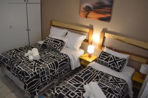 a hotel room with two beds and a lamp at Wanjara's Nest in Windhoek