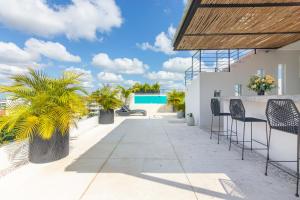a patio with chairs and a table and palm trees at Toh House Luxury by Boutique Apartments MX in Playa del Carmen