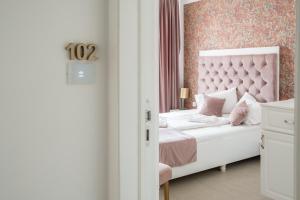 a bedroom with a white bed with a pink headboard at Hotel Marabella in Sibiu