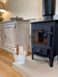 a kitchen with a stove and a bucket of wood at Grange Barn, Ashford In The Water in Great Longstone