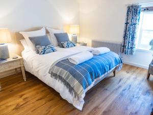 a bedroom with a large bed with blue and white pillows at Grange Barn, Ashford In The Water in Great Longstone