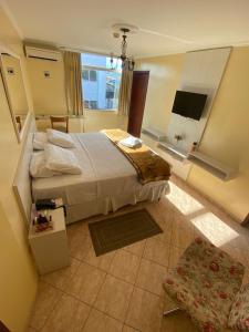 a hotel room with a large bed and a television at Pousada Emaús in Cruzeiro