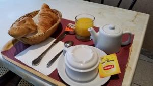 a tray with a tea pot and bread and a glass of orange juice at Hotel Paris Bercy in Paris