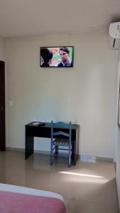 a tv hanging on a wall above a desk at Suíte para Hospedagem em Porto Belo in Porto Belo