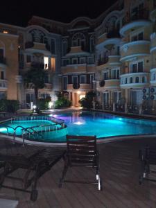 a swimming pool in front of a building at night at Marina Studio in Ravda