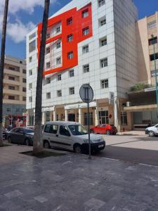 biały samochód zaparkowany przed dużym budynkiem w obiekcie Appartement Ville Nouvelle Bio w mieście Meknès