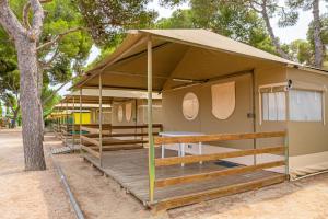 a tent with a wooden deck next to a tree at Camping Relax Sol in Torredembarra