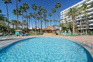 a swimming pool with palm trees and a building at Bull Eugenia Victoria & Spa in Playa del Ingles
